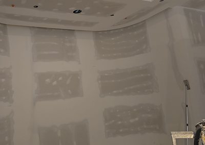 A curved drywall wall and bulkhead with every butt joint and screw head taped and coated, ready for sanding.